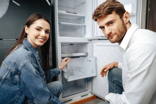 Jovem casal selecionando novo refrigerador na loja de eletrodomésticos — Fotografia de Stock