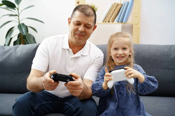 Avô e neta jogando videogames em casa. — Fotografia de Stock