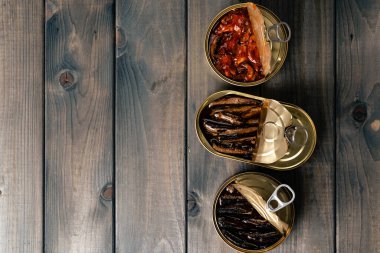 Ahşap zemin üzerinde balık rezervleri olan açık konserve kutularının üst görünümü