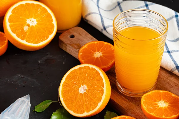 Стекло апельсинового сока и апельсины на столе — стоковое фото