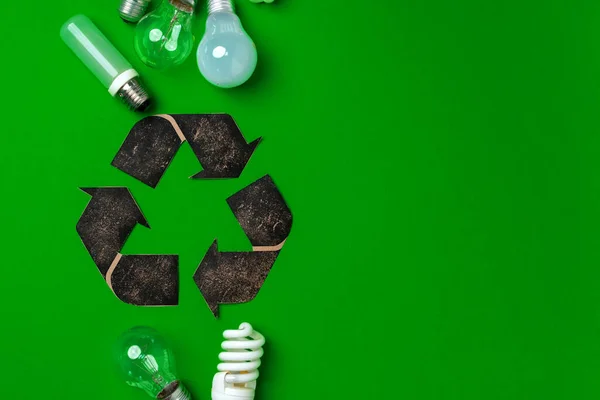 Lâmpada e sinal de reciclagem no fundo verde — Fotografia de Stock