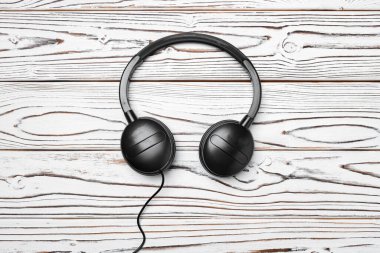 Tahta arka planda kablo olan siyah kulaklıklar.
