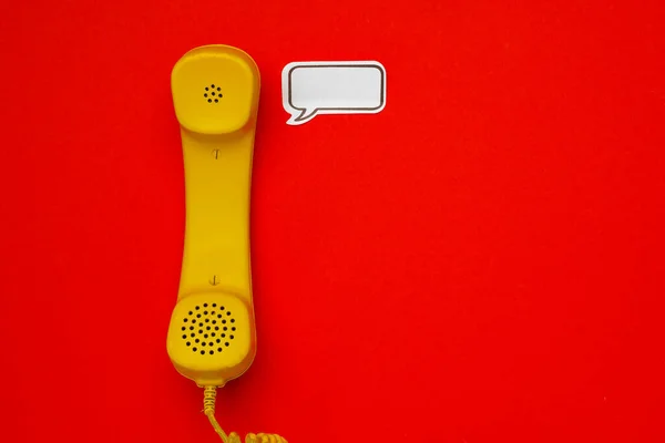 Altavoz amarillo del teléfono y burbuja del habla sobre fondo rojo — Foto de Stock