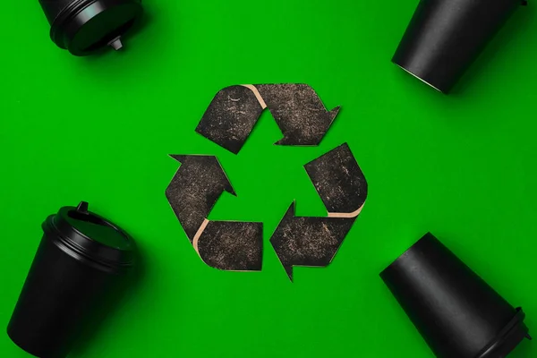 Copo de café descartável e sinal de reciclagem no fundo verde — Fotografia de Stock