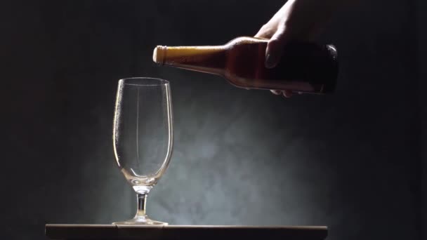 Пиво наливается в стакан на черном фоне — стоковое видео
