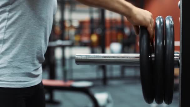 Männlicher Athlet nimmt in einem Fitnessstudio Gewicht von einer Stange ab — Stockvideo