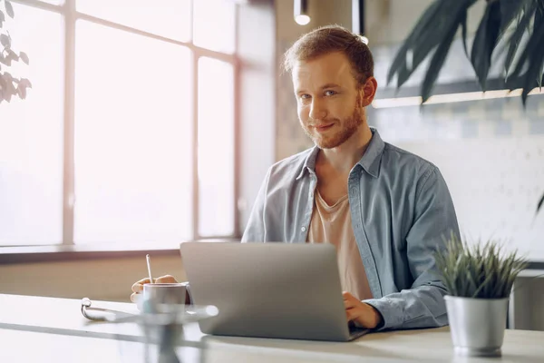 Jungunternehmer macht sich Notizen im Notizblock, während er am Arbeitstisch im modernen Büro sitzt — Stockfoto