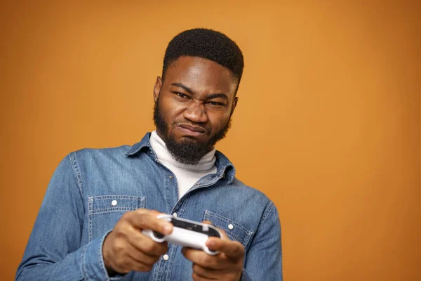 Genç Afro-Amerikan adam elinde joystick ile video oyunları oynuyor, sarı arka plan — Stok fotoğraf