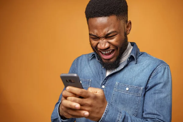 Angry frustrated young african american man recieved message with bad news on his phone