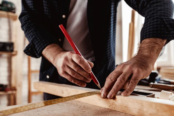 Ο ξυλουργός κάνει σημάδια από μολύβι σε μια ξύλινη σανίδα. — Φωτογραφία Αρχείου