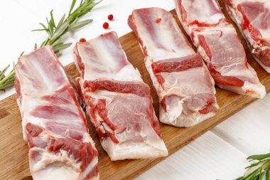 Beyaz arka planda tahta tahtada çiğ et kaburgaları.