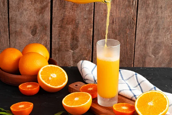 Orange juice pouring from the bottle into the glass — Stock Photo, Image