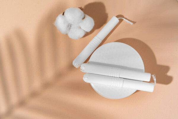 Hygienic tampons and cotton flower on paper background