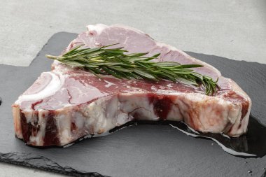 Gri masada yağda marine edilmiş çiğ biftek.