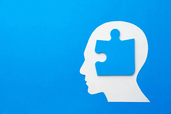 Papercut head with jigsaw puzzle pieces on blue background