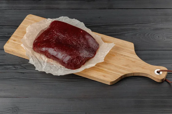 Fígado de carne crua em tábua de madeira na mesa — Fotografia de Stock