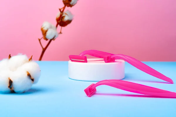 Rózsaszín eldobható borotvák és pamutvirág kék papíron — Stock Fotó