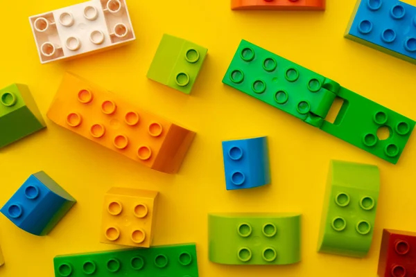 노란색 배경에 흩어진 아이들 장난감 제작 자의 세부 사항 — 스톡 사진