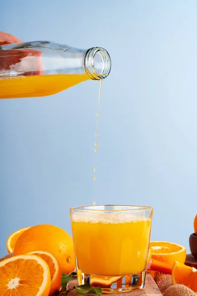 Orange juice pouring from the bottle into the glass — Stock Photo, Image