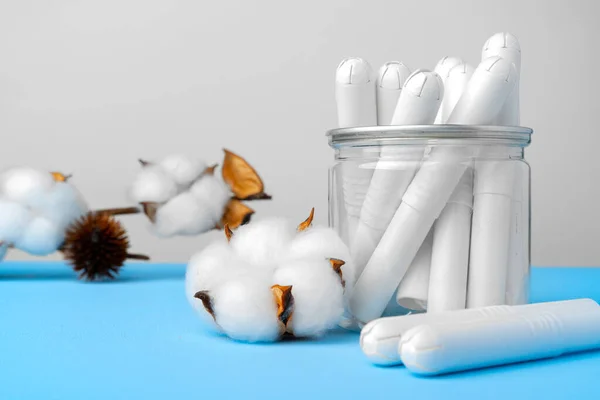 Weibliche medizinische Tampons und Baumwollblume auf blauem Papier Hintergrund — Stockfoto