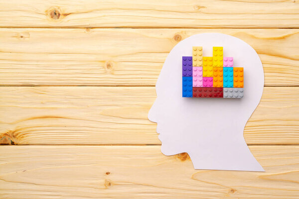 Papercut silhouette of human head with colorful constructor pieces