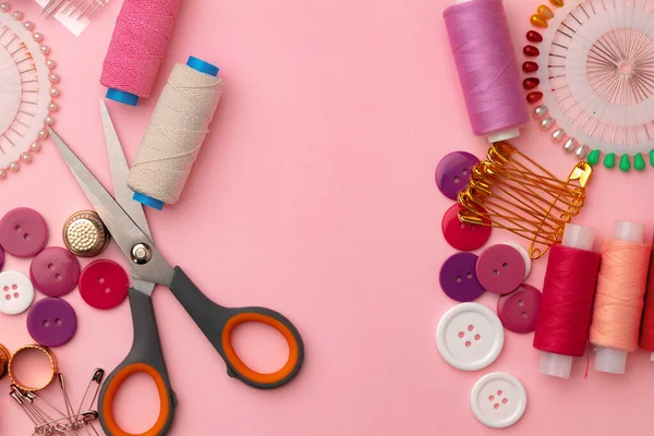 Sewing accessories including thread spools and pins on pink background — Stock Photo, Image