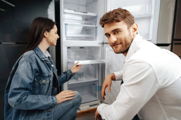 젊은 부부가 가정용품 가게에서 새로운 냉장고를 고르고 있다 — 스톡 사진