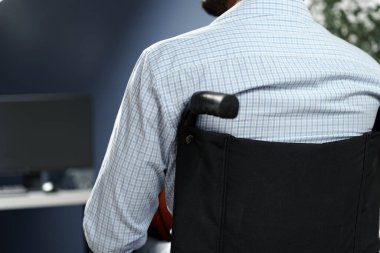 Evde tekerlekli sandalyede oturan engelli bir adam.