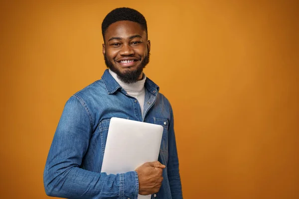 Sarı arka planda dizüstü bilgisayarı olan genç bir Afro-Amerikan. — Stok fotoğraf