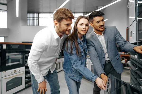 Manlig butiksbiträde hjälper unga par att välja ny hushållsapparat — Stockfoto