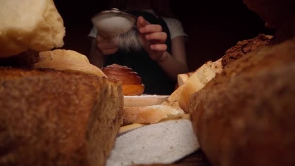 Mãos de um padeiro derramando açúcar em pó em pão doce recém-assado — Vídeo de Stock