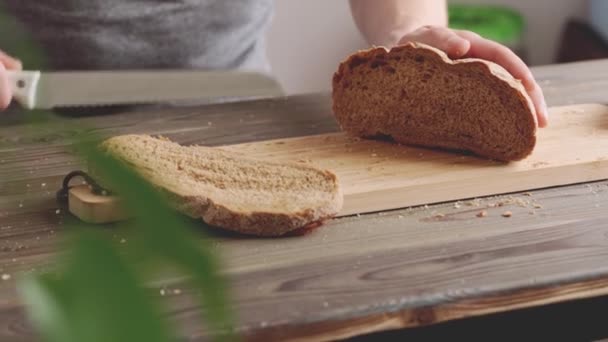 Händer av en kvinna skära bröd limpa på trä skärbräda — Stockvideo