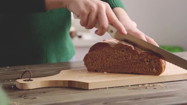 Händer av en kvinna skära bröd limpa på trä skärbräda — Stockvideo