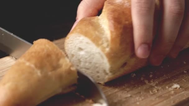 Handen van een vrouw die brood snijdt op een houten snijplank — Stockvideo