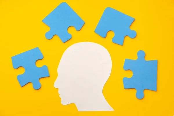 Papercut hoofd silhouet met puzzelstukjes op gele achtergrond — Stockfoto