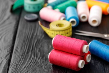 Siyah ahşap yüzeyde renkli dikiş aletleri