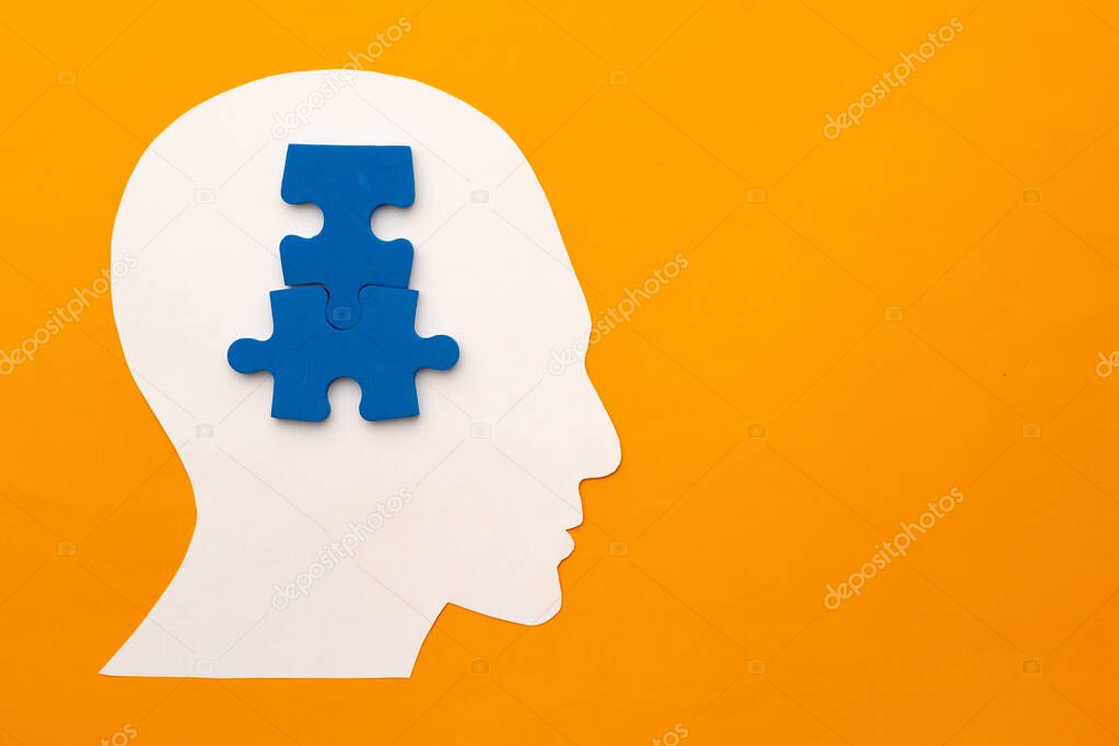 Papercut head silhouette with puzzle pieces on yellow background