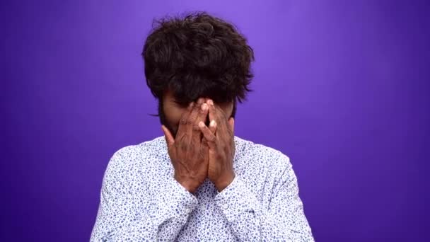 Chateado afro-americano começa a chorar, fechando o rosto com as mãos, fundo roxo — Vídeo de Stock