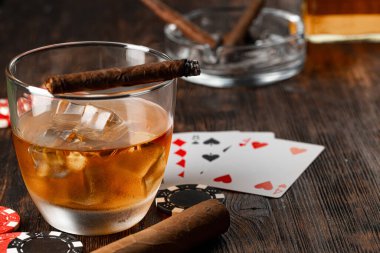 Küba purosu, viski bardağı ve cipsler masada.