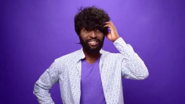 Genç Afrikalı Amerikalı adam düşünüyor, mor stüdyo geçmişi var.