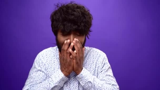 Homme afro-américain bouleversé commence à pleurer, le visage de fermeture avec les mains, fond violet — Video