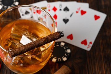 Küba purosu, viski bardağı ve cipsler masada.