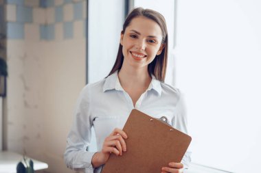 Genç ve çekici bir iş kadınının portresi ofiste pano tutuyor.