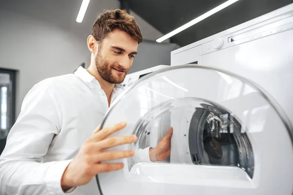 Hombre joven eligiendo una nueva lavadora en la tienda de electrodomésticos — Foto de Stock
