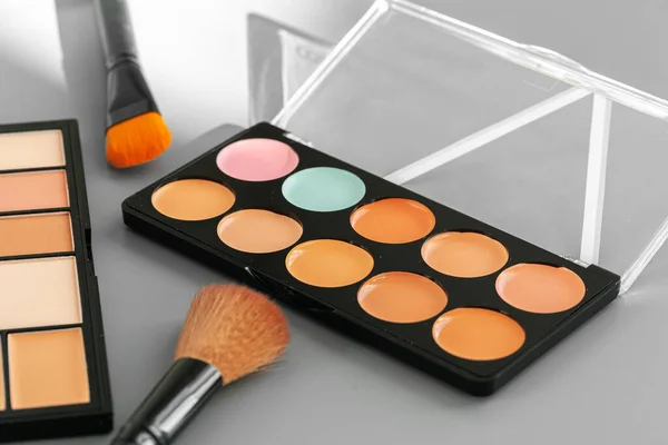 Paleta de maquillaje con correctores de colores sobre fondo gris — Foto de Stock