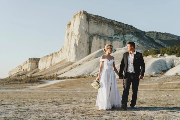 Mariée et marié debout contre grand rocher blanc — Photo