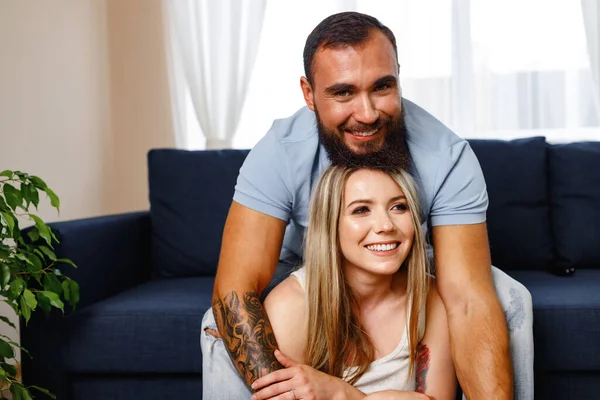 Feliz casal sorridente sentado no sofá azul na sala de estar — Fotografia de Stock
