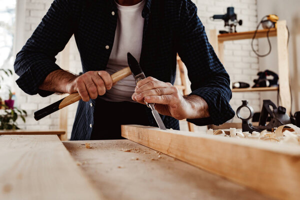 Hands of a carpenter working with chisel and hammer