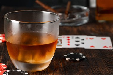 Küba purosu, viski bardağı ve cipsler masada.