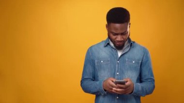 Genç Afrikalı Amerikalı adam elinde akıllı telefonla zaferi kutluyor.